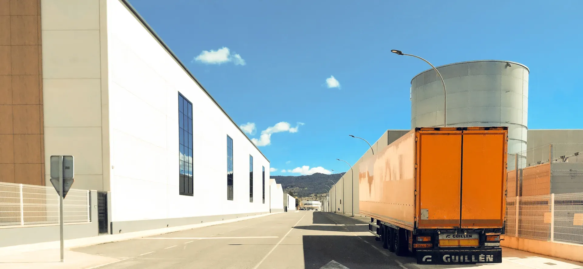 White industrial building with orange truck trailer under blue sky | Found Minimalism | Alicante province | MarkOWiHu Photographer Fotógrafo • markowihu.es