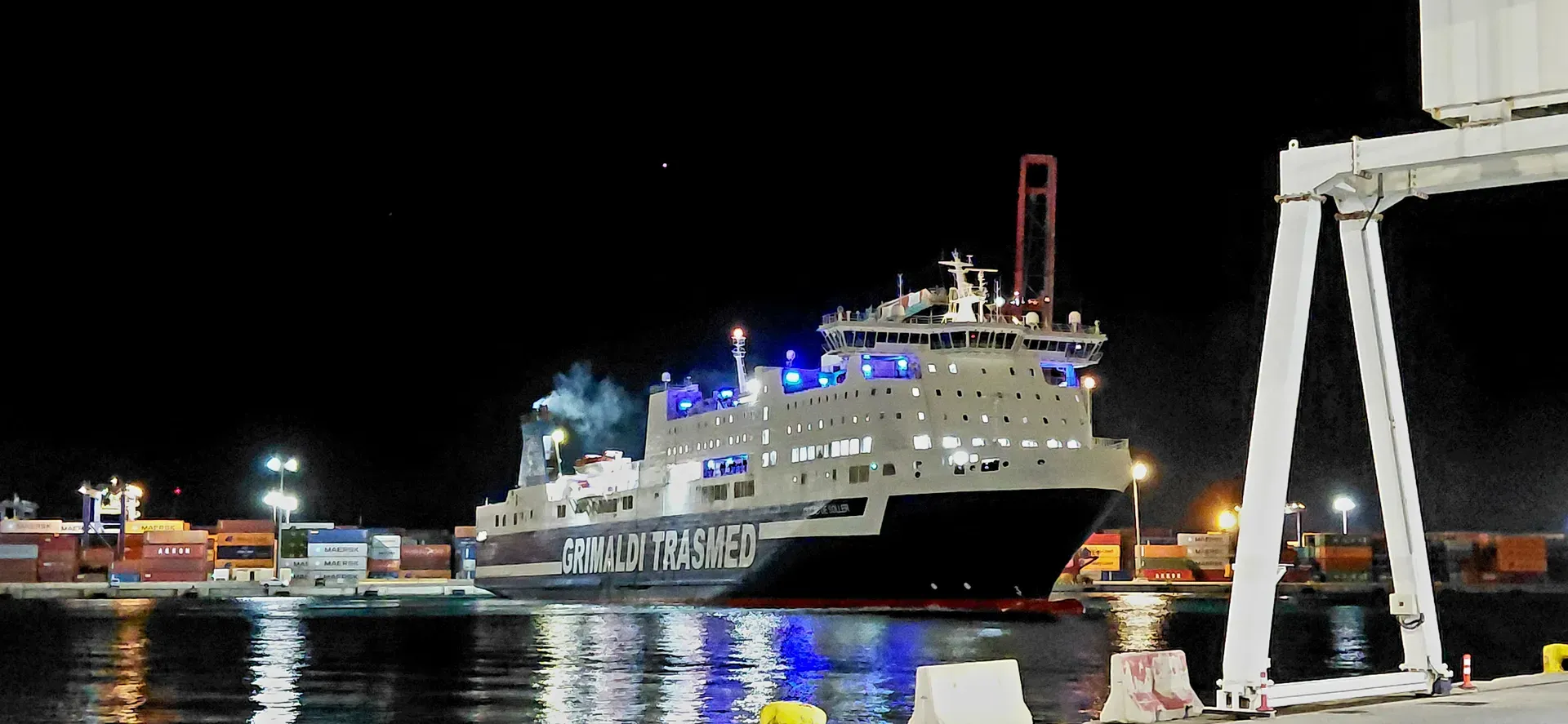 Illuminated ferry hull at night port framed by white gantry crane and blue deck lights | Maritime Night Photography | Alicante province | MarkOWiHu Photographer Fotógrafo • markowihu.es
