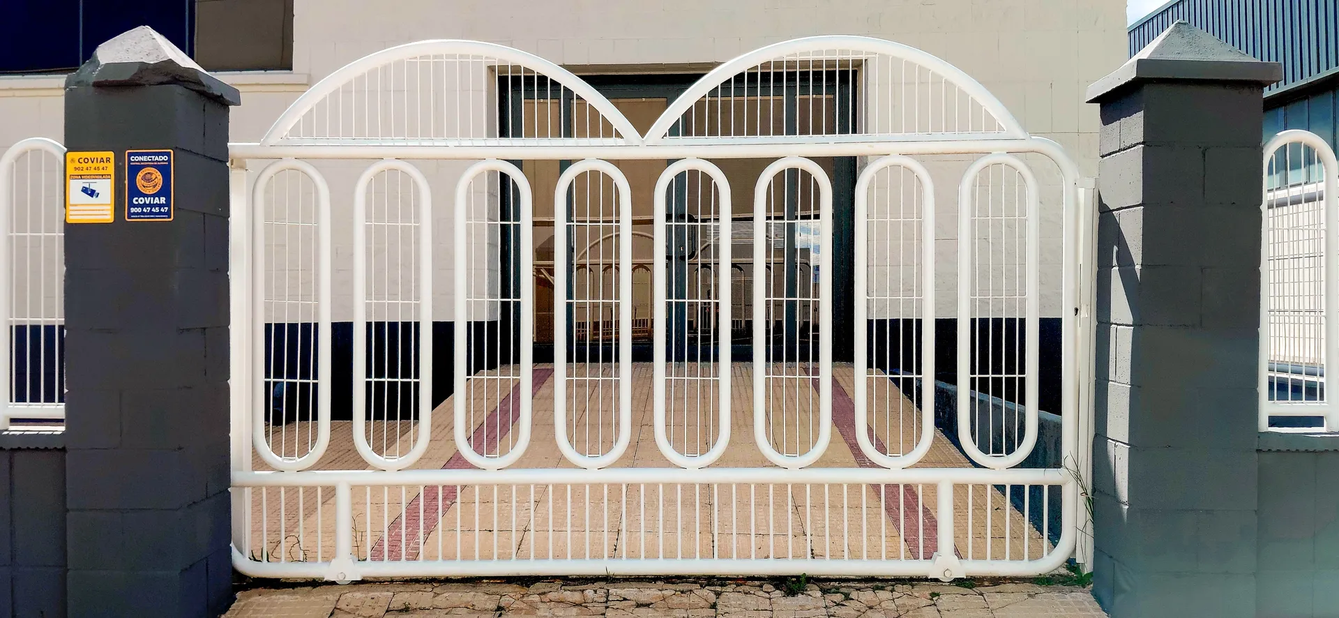 Symmetrical white arched iron gate set against dark urban building entrance