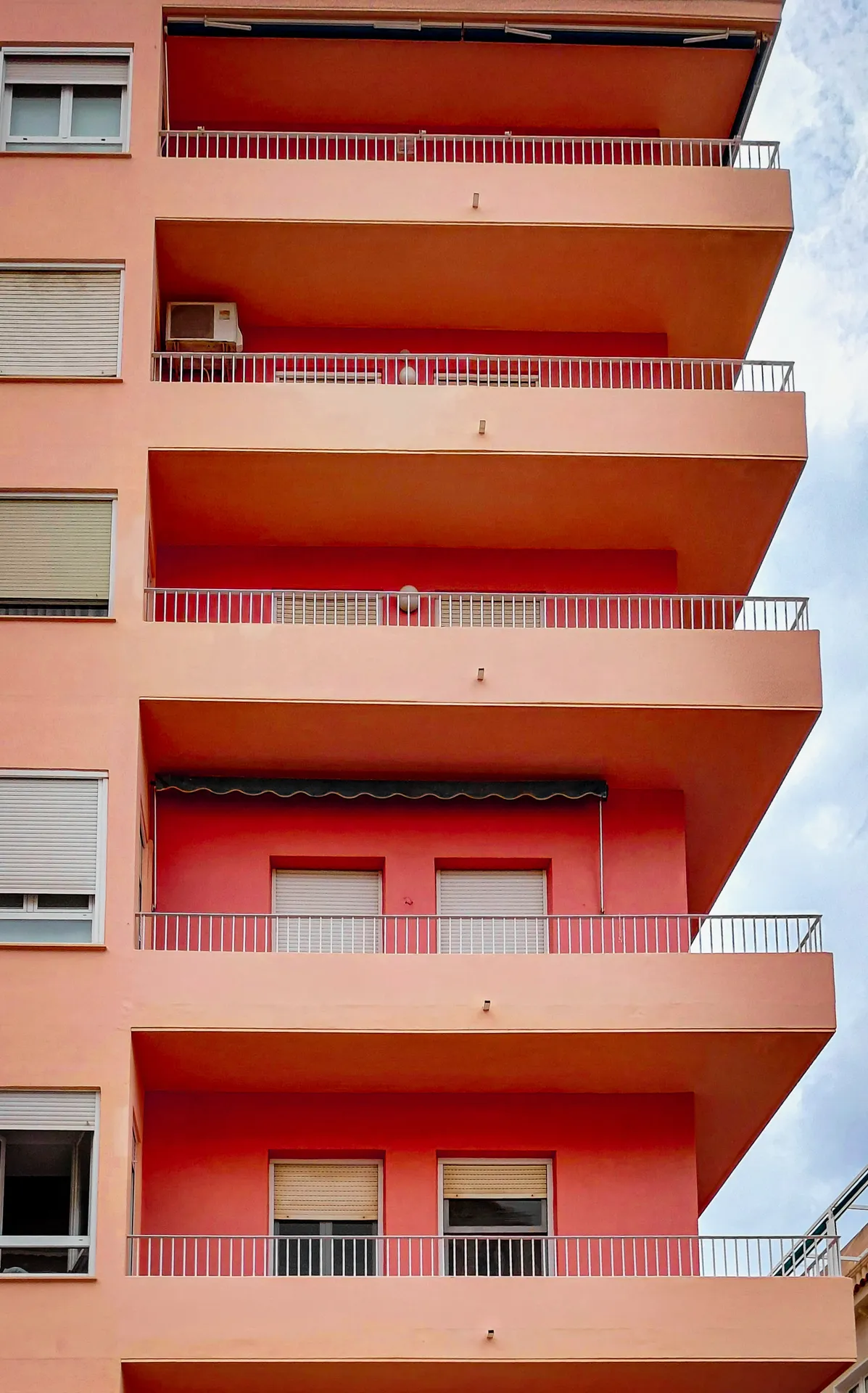 Terracotta red apartment balconies stacked vertically against a clear blue sky in Mark Rothko style