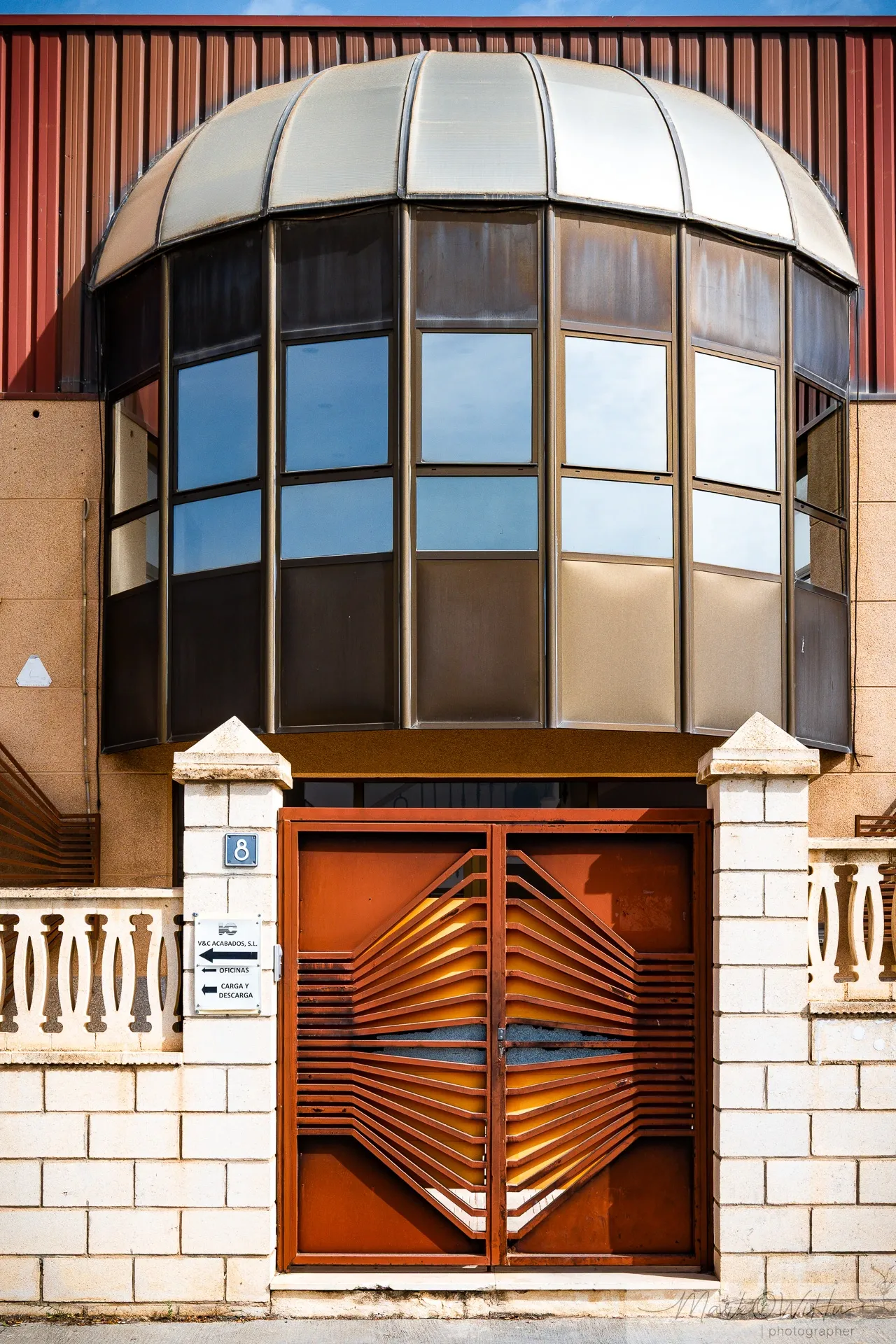 Modernist copper dome structure and arched iron security gate on an urban office building