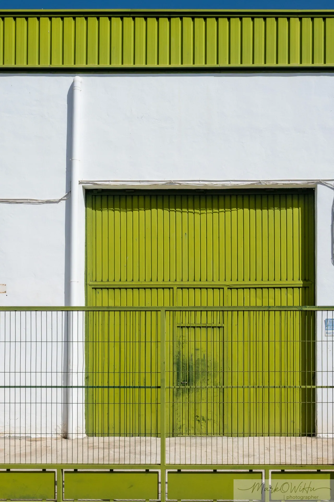 Symmetrical green industrial loading doors with a central white pillar and staircase