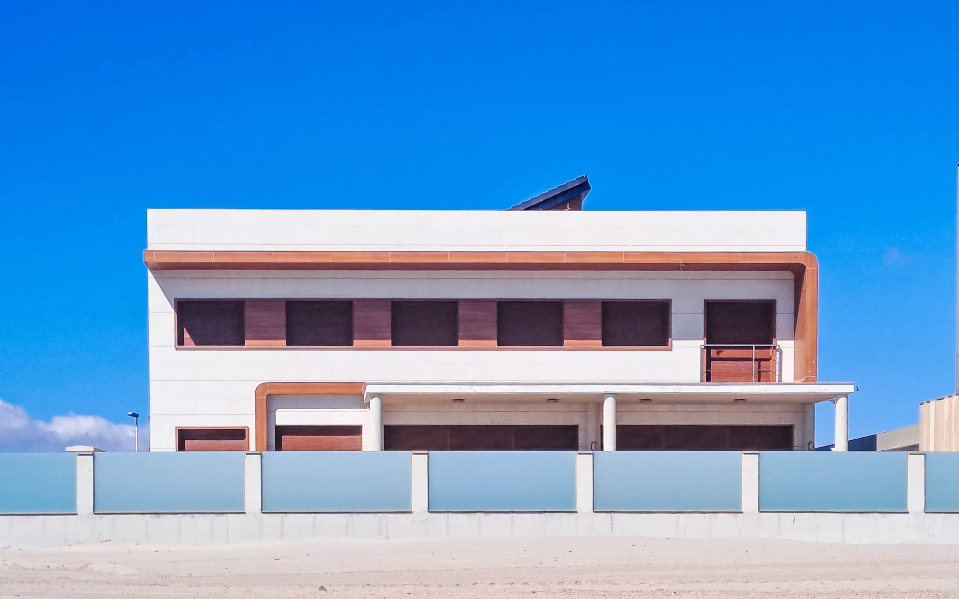 Rectangular pattern modernist white house with terracotta trim isolated under a deep blue sky