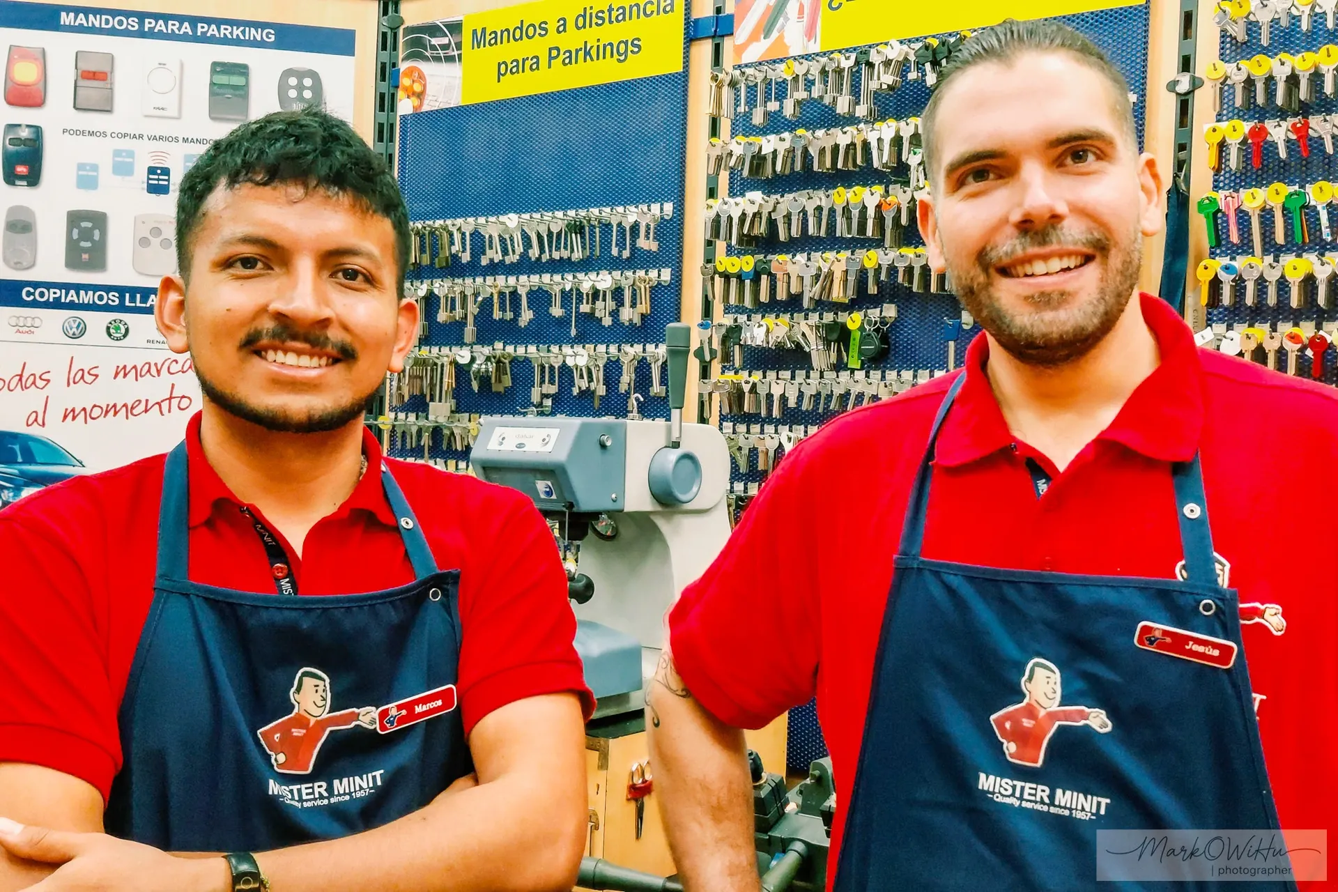 Two friendly shopkeepers in matching red aprons at store entrance | Street & Humanity | Alicante province | MarkOWiHu Photographer Fotógrafo • markowihu.es